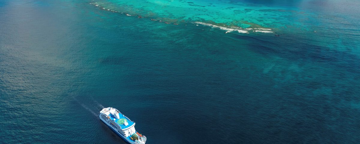 Aranui Cruises’ ship sailing past a turquoise reef in French Polynesia