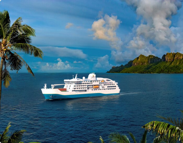 Aranui Cruises’ ship at anchor off a green, mountainous coast