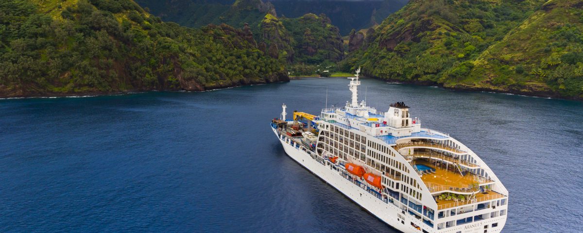 Aranui 5 at anchor in a steep green valley bay in the Marquesas